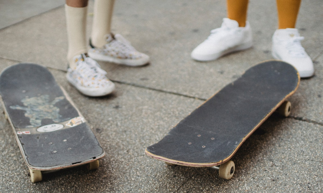 Two skateboards on the ground showing worn skateboard grip tape