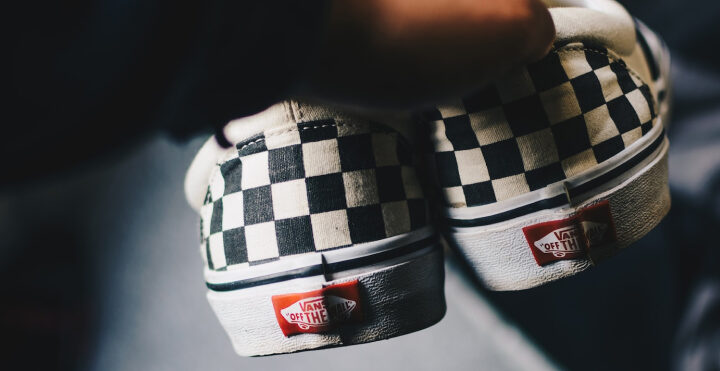 holding a pair of vans skateboarding shoes