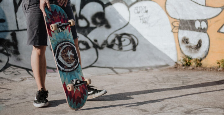man holding a skateboard in skate park