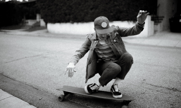 black and white photo of man squatting on skateboard